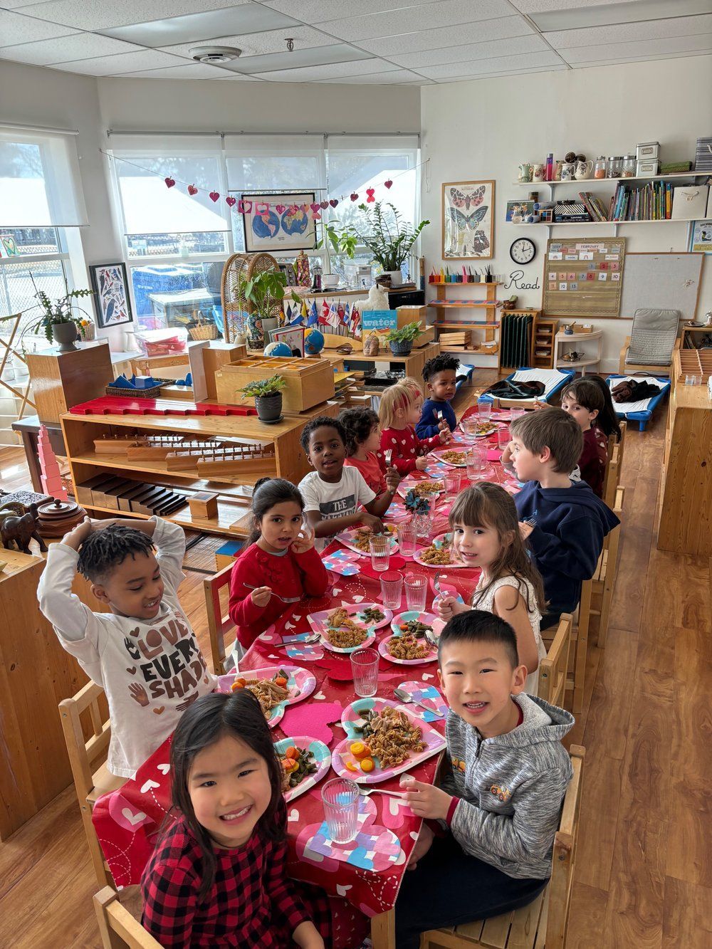 A group of children are sitting at a long table eating food.