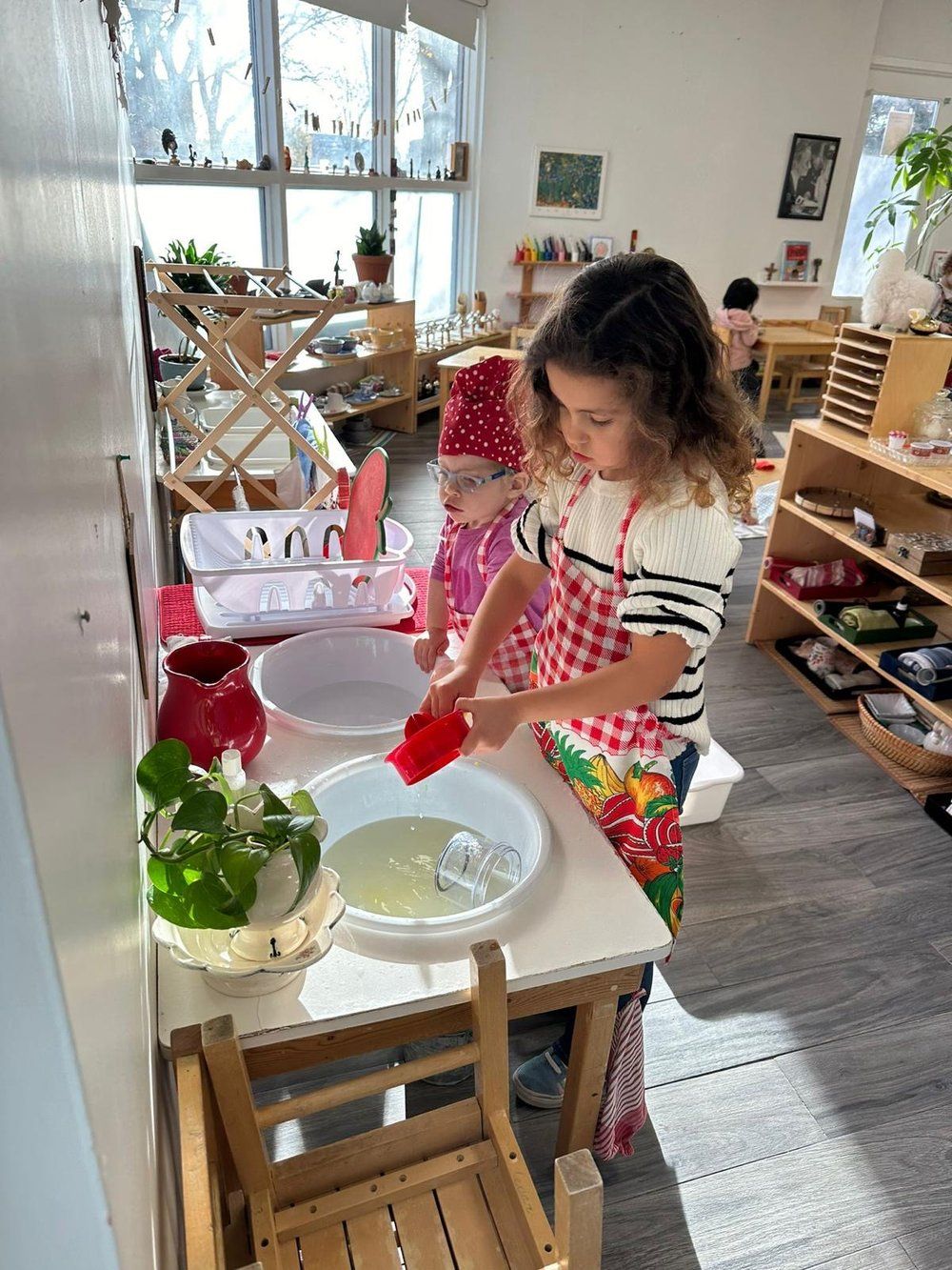 Two little girls are playing with water in a room.