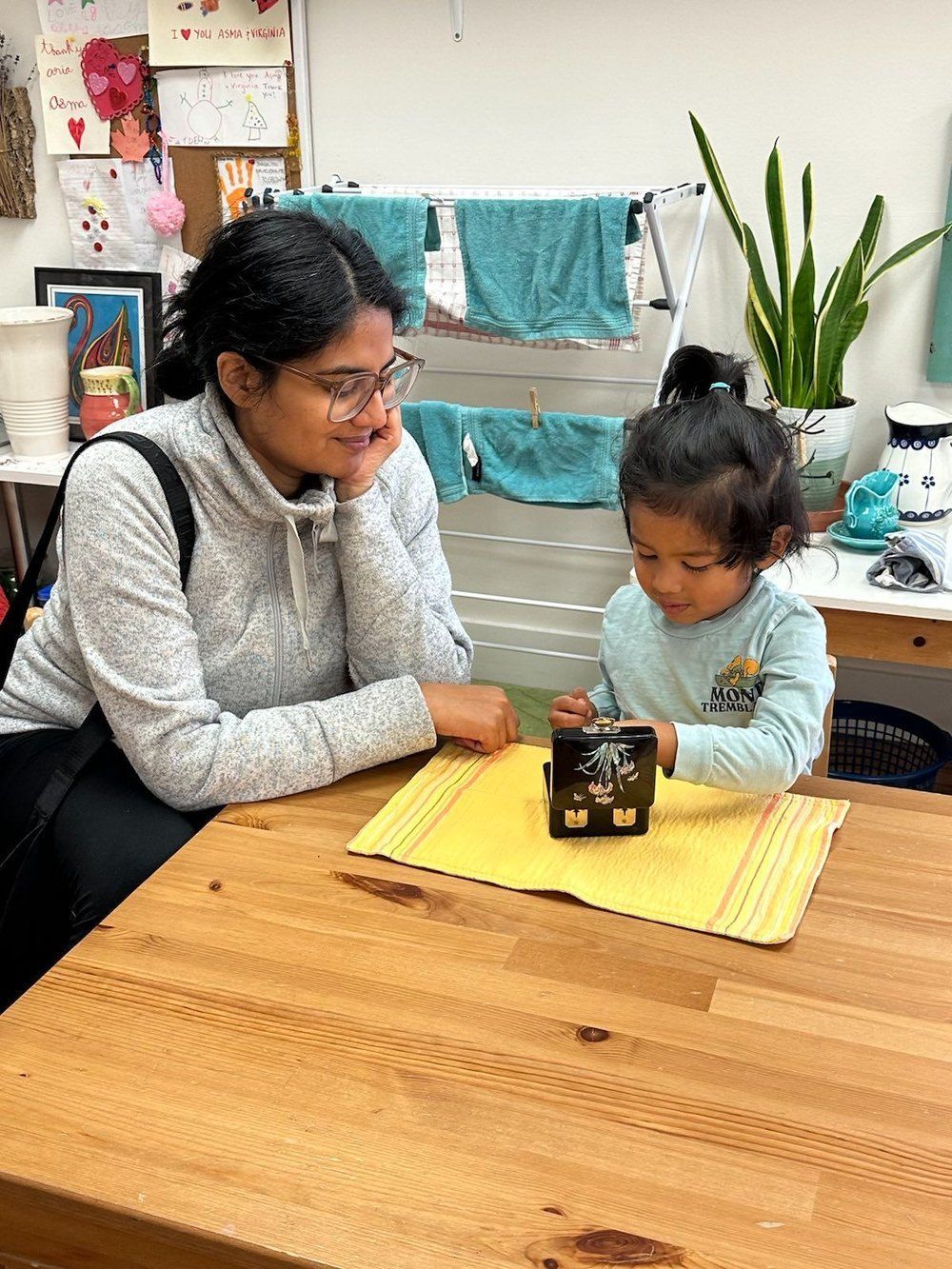 A woman is sitting at a table with a little girl.