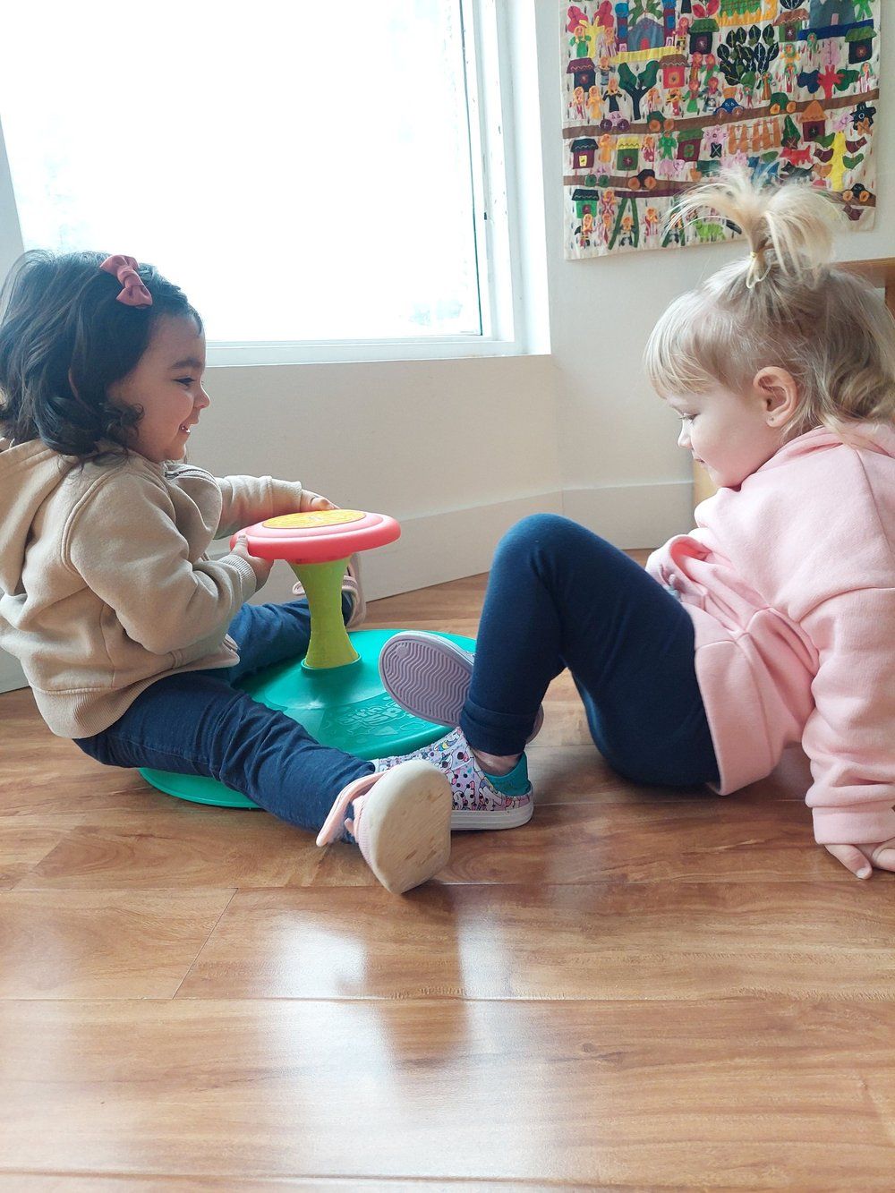 Two little girls are sitting on the floor playing with toys.
