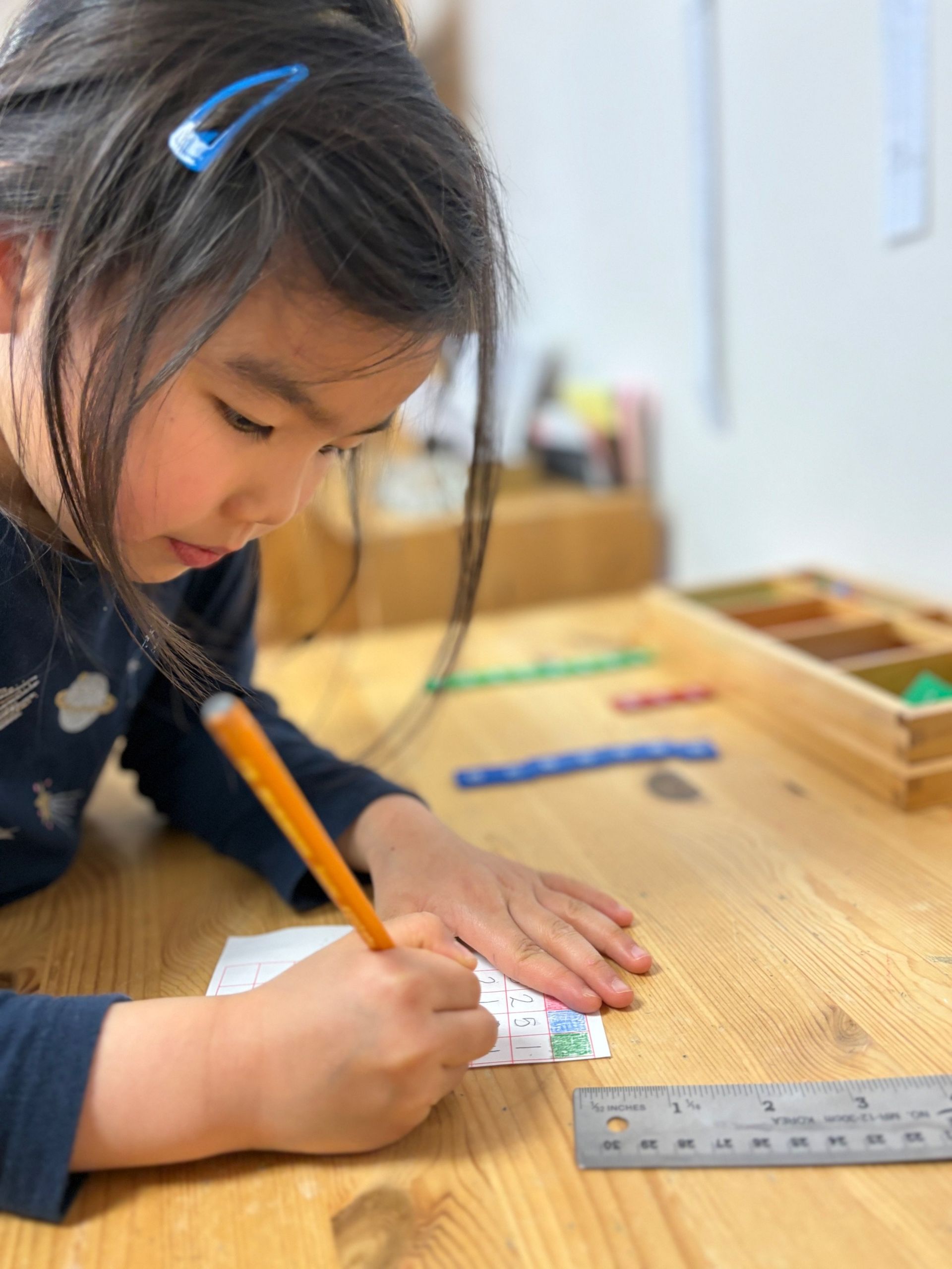 A little girl is writing on a piece of paper with a pencil