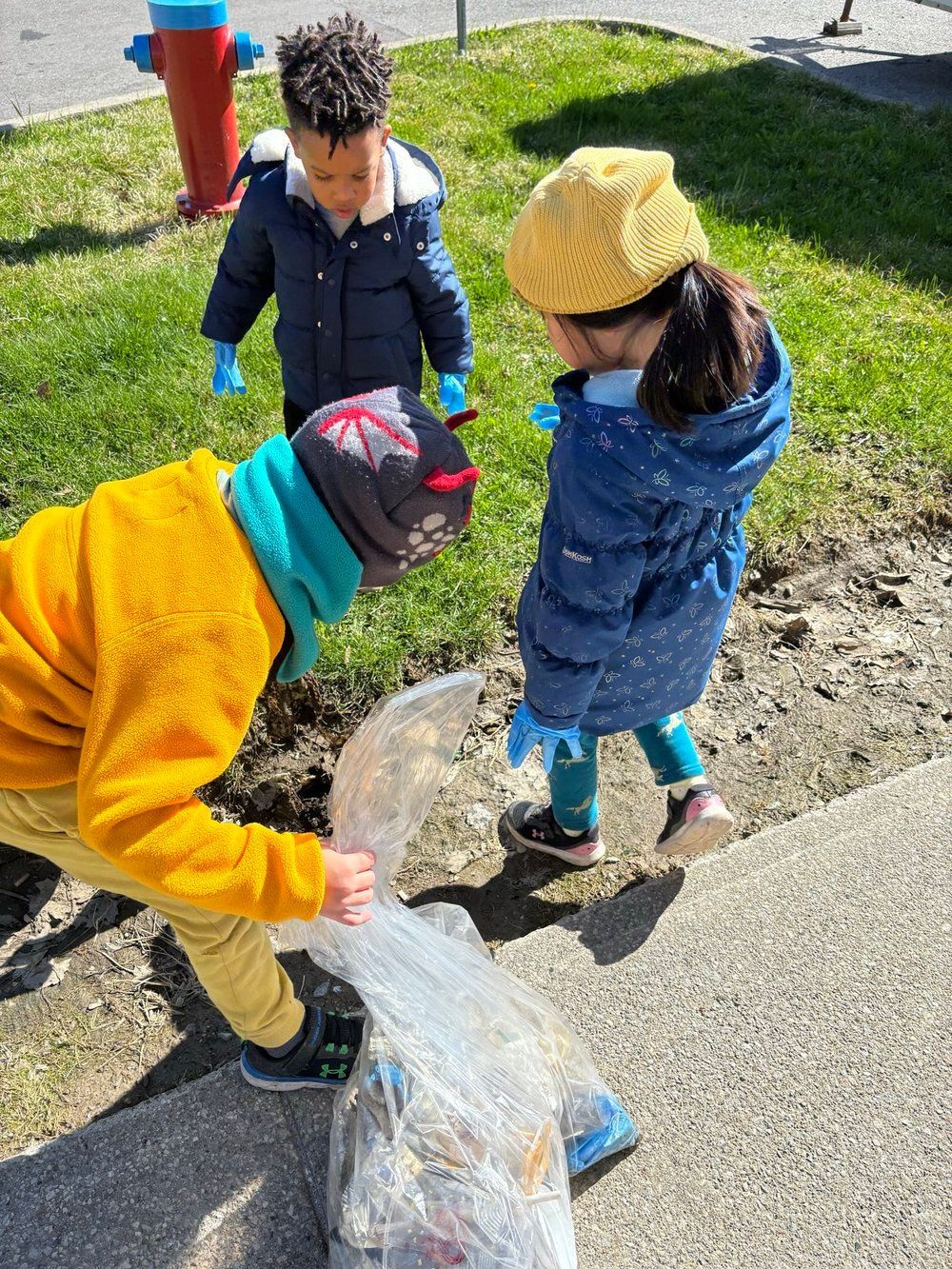 A boy and a girl are picking up trash on the sidewalk.