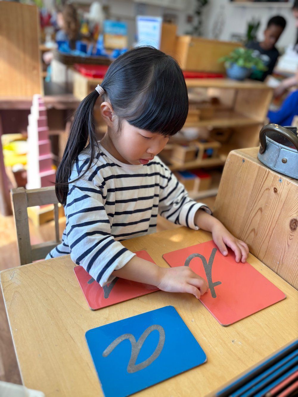 A little girl is sitting at a table playing with letters.