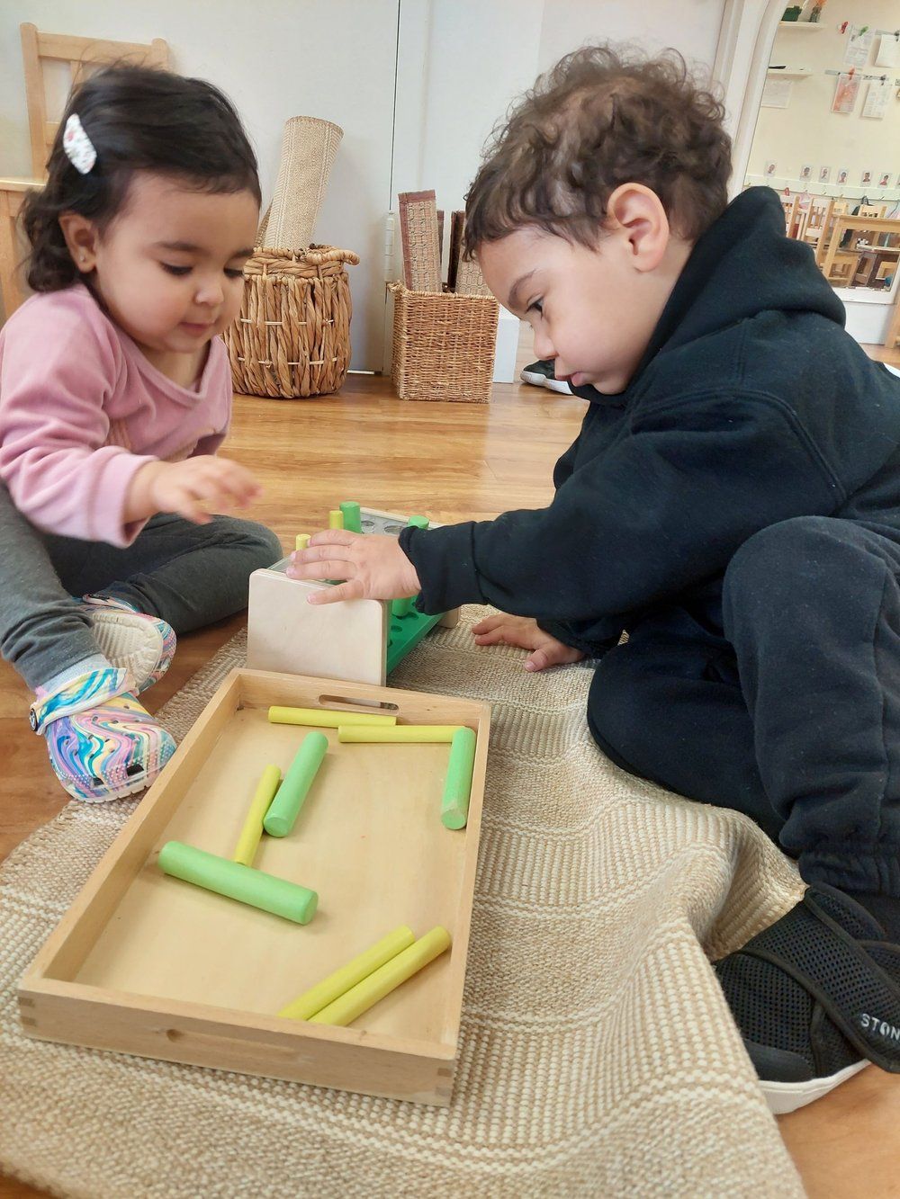 A boy and a girl are playing with toys on the floor.