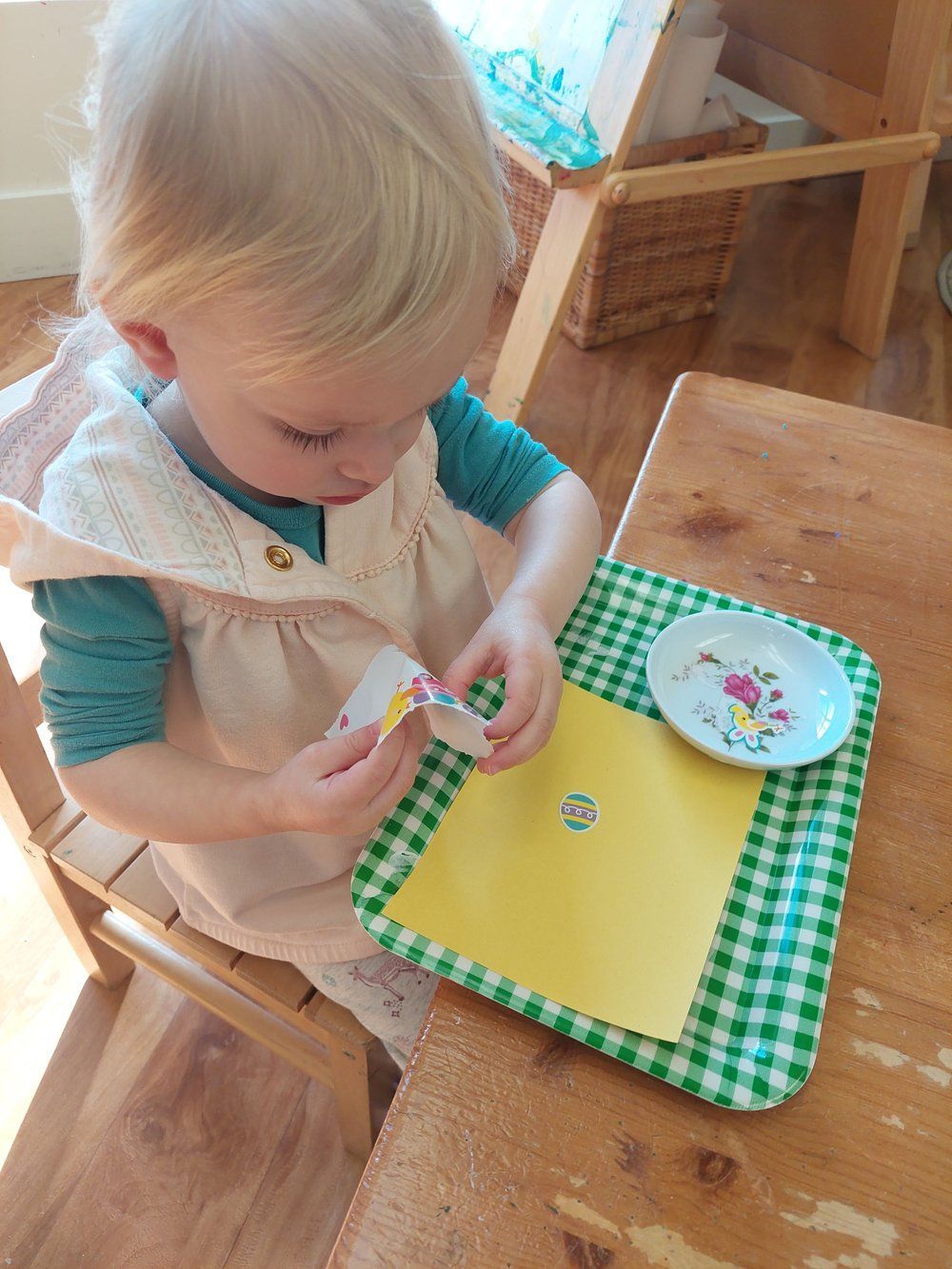 A little girl is sitting at a table playing with a piece of paper.