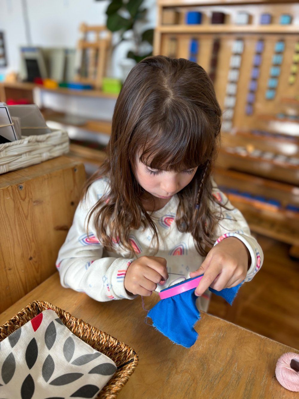 A little girl is sitting at a table cutting a piece of paper.