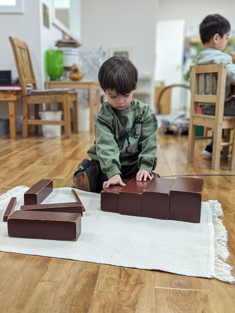 A young boy is sitting on the floor playing with wooden blocks.