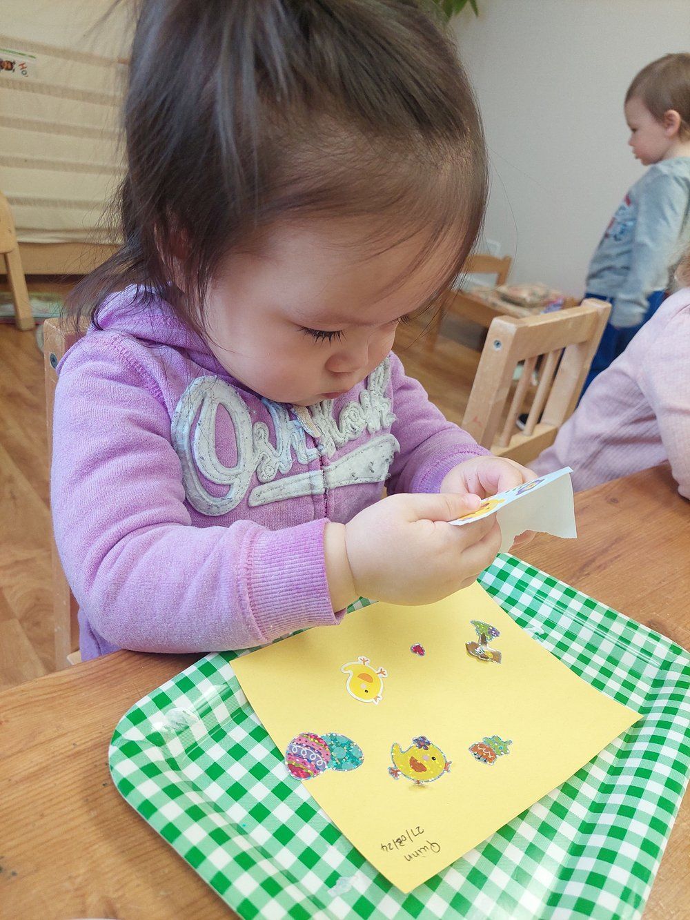 A little girl is sitting at a table playing with a piece of paper.