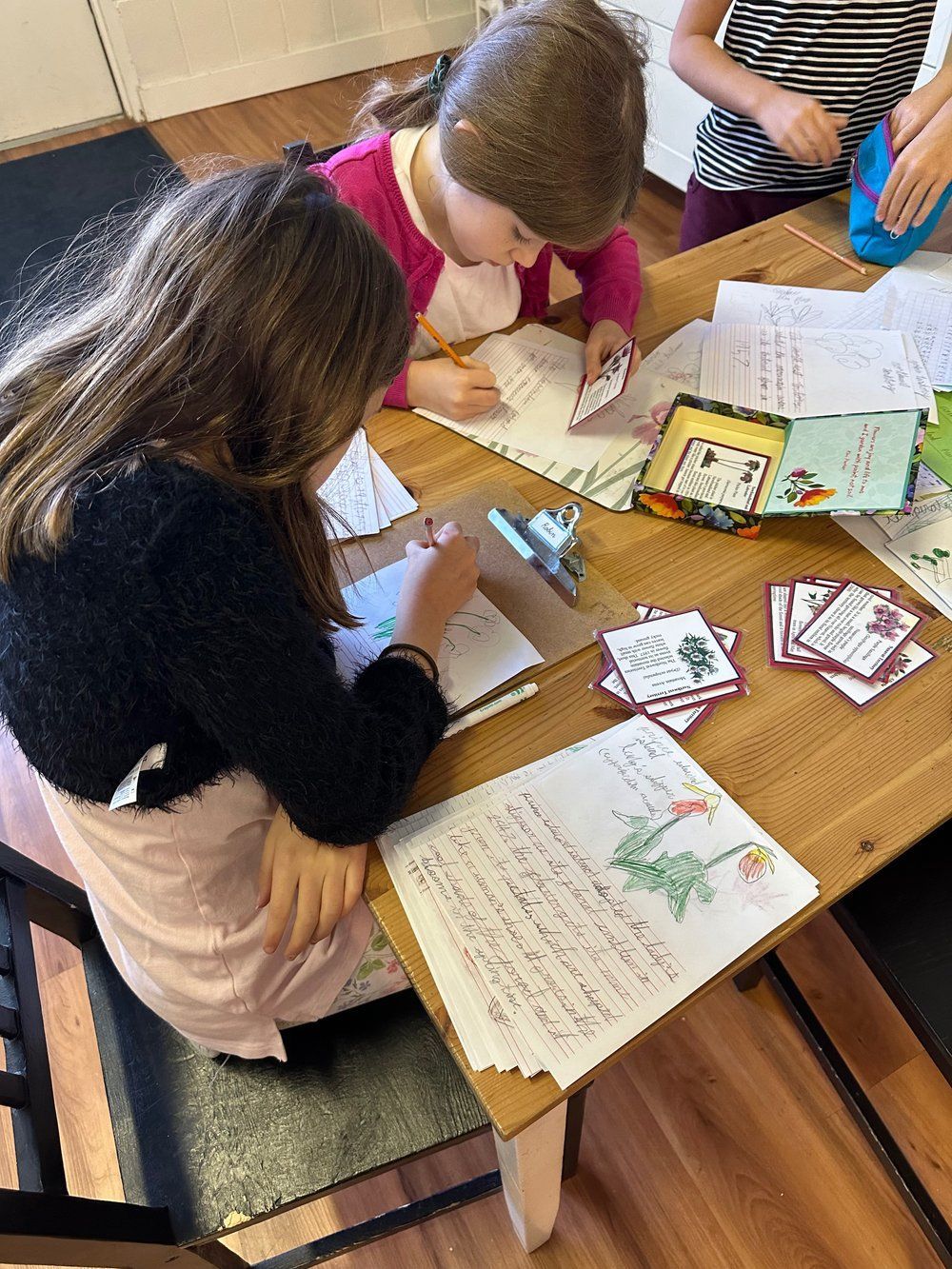 A group of children are sitting at a table writing letters.