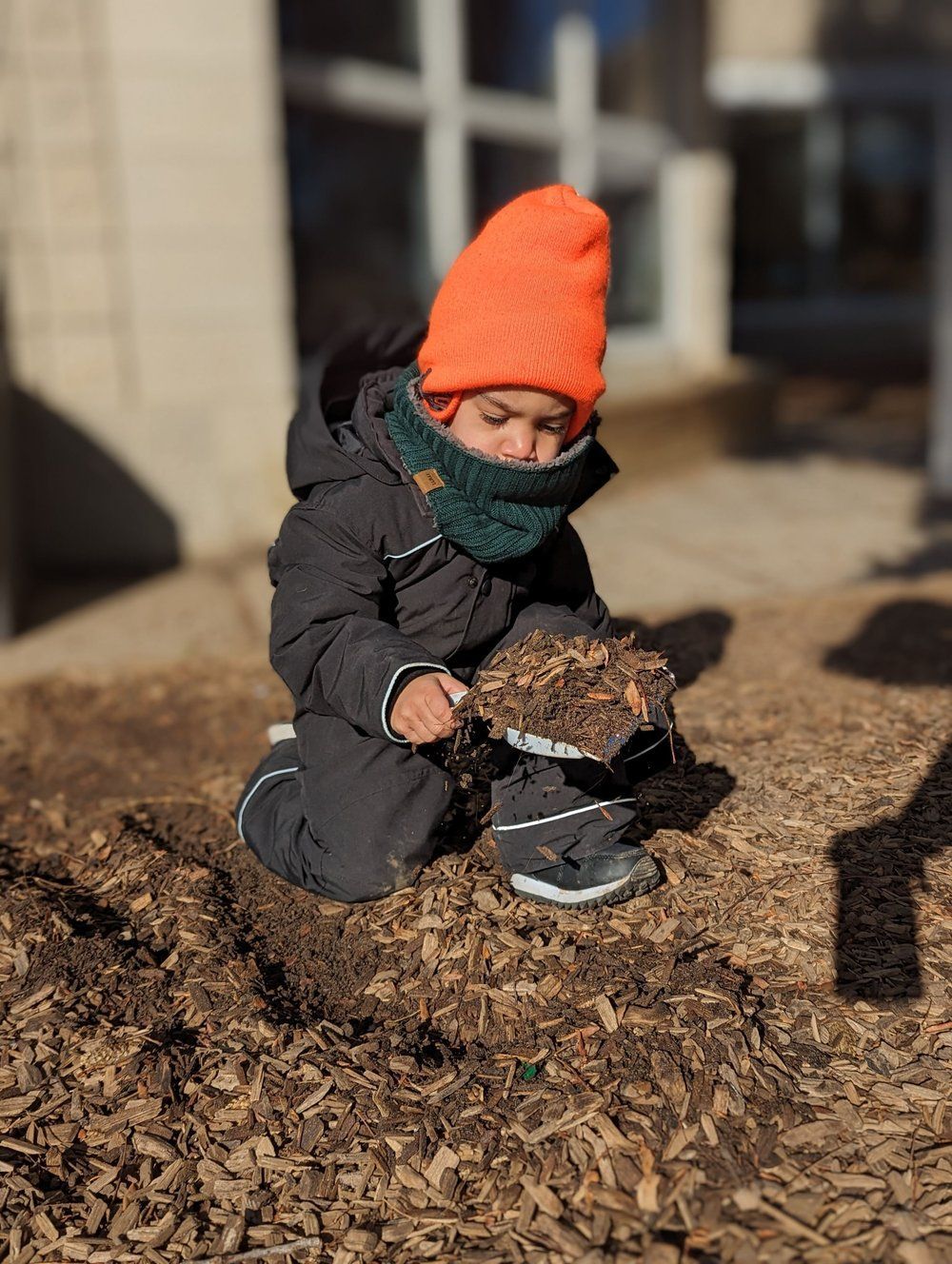 A little boy wearing an orange hat is playing in the dirt.