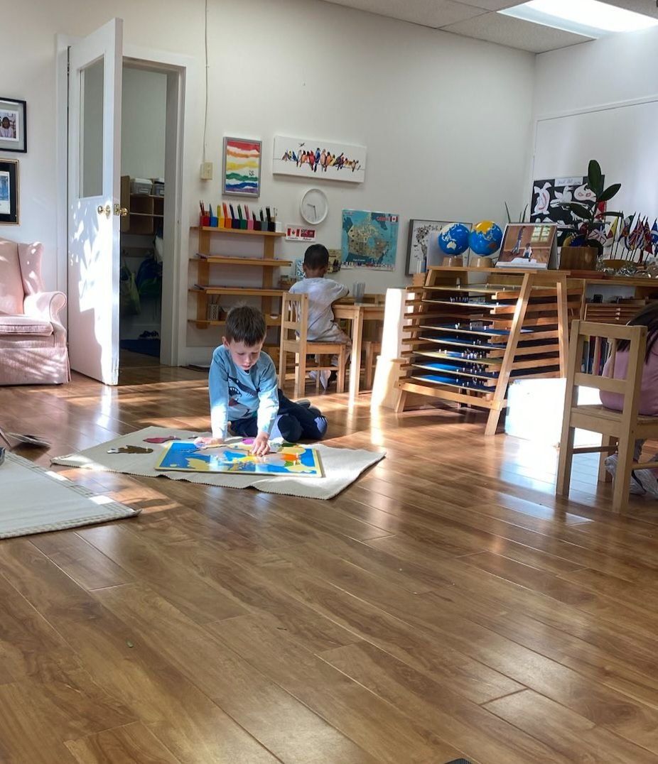 A little boy is sitting on the floor playing with a puzzle.