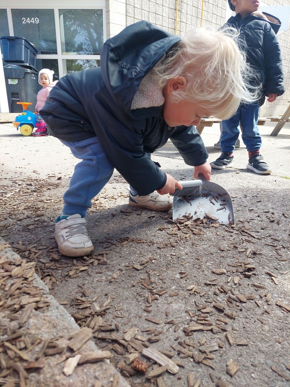 A little boy is playing with a shovel in the dirt.