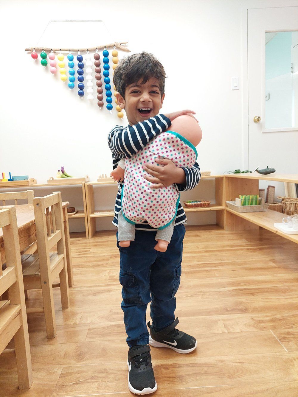A young boy is holding a baby doll in a room.