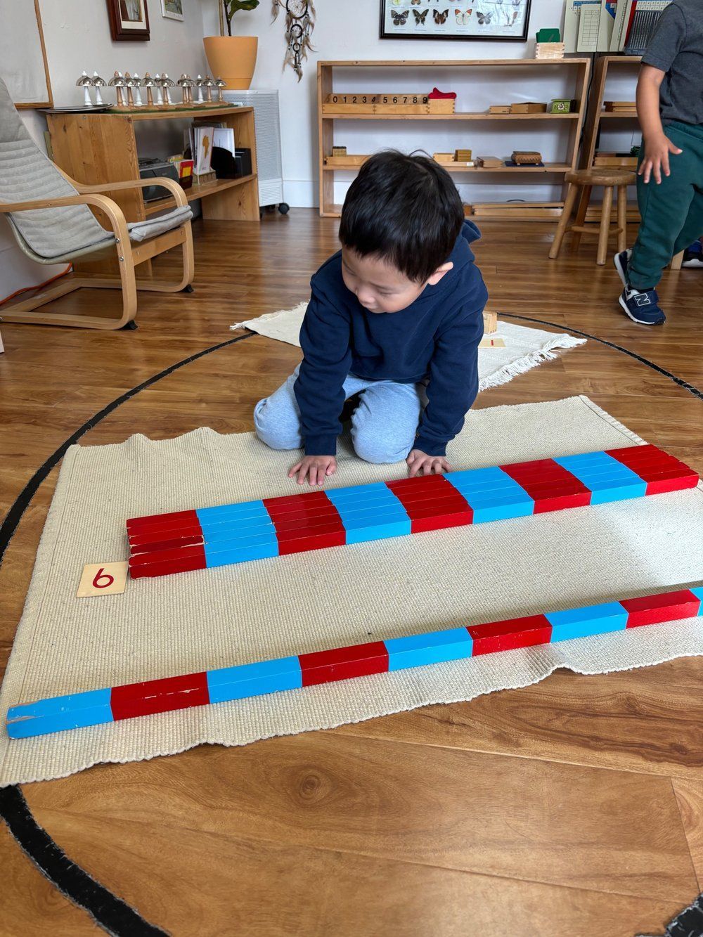A young boy is playing with red and blue blocks on the floor.