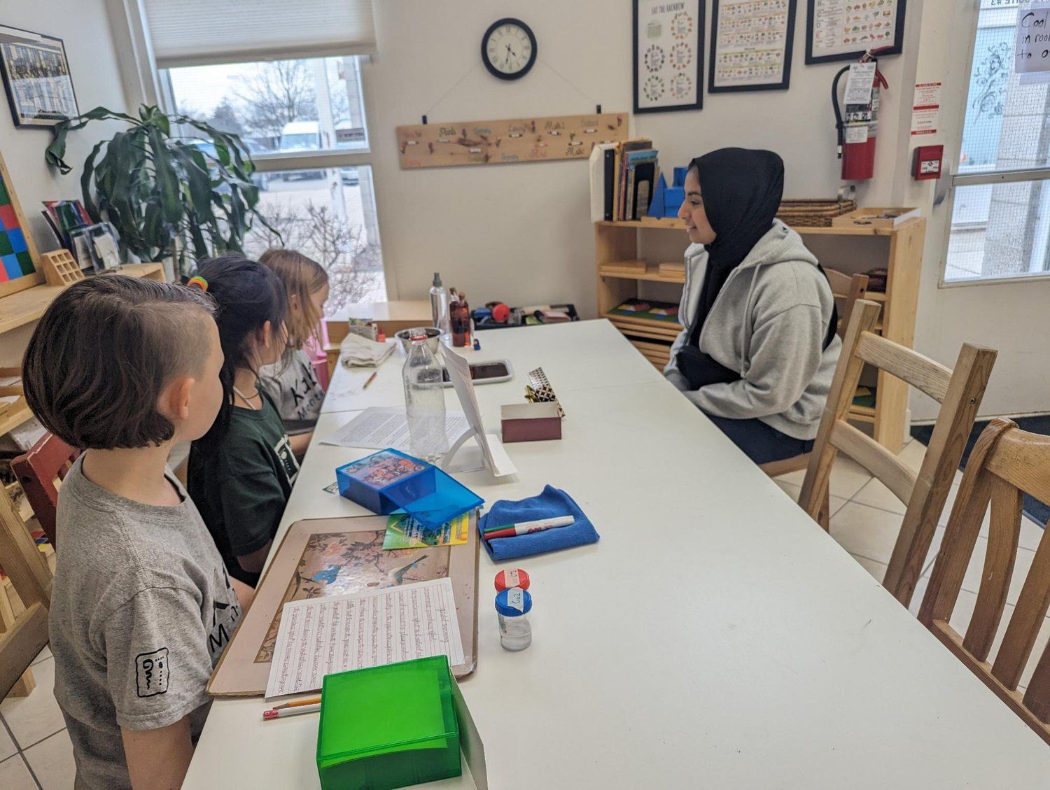 A group of children are sitting at a table in a classroom.