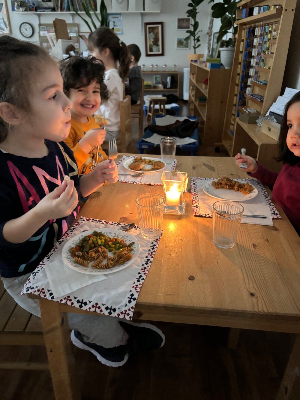 A group of children are sitting at a table eating food.