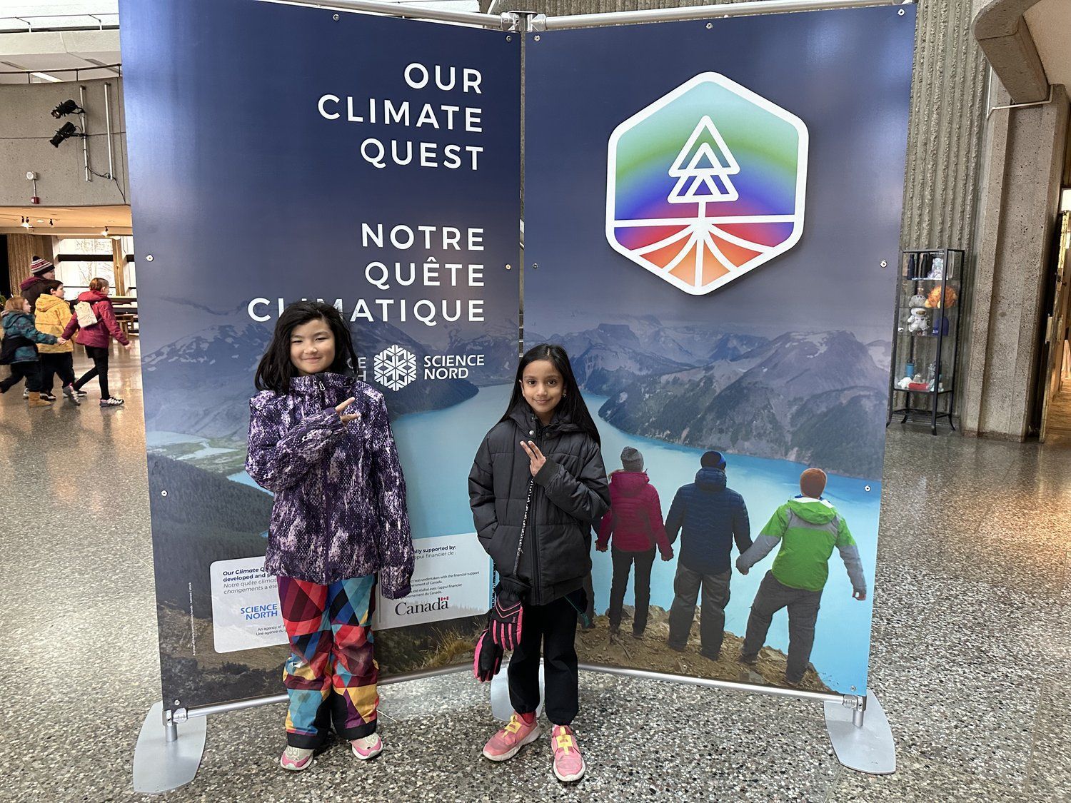 Two young girls are standing in front of a sign that says our climate quest