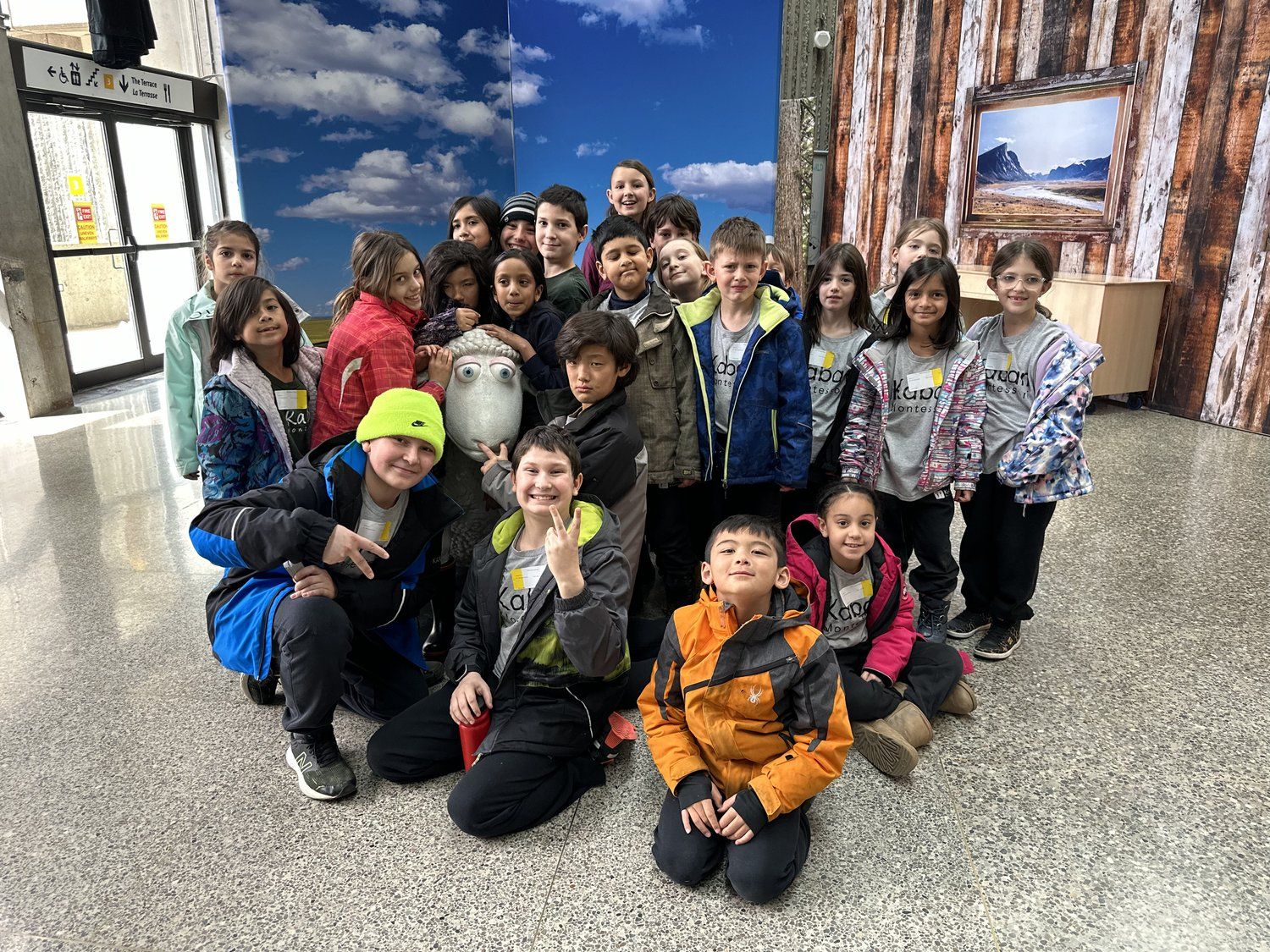 A group of children are posing for a picture in a hallway.