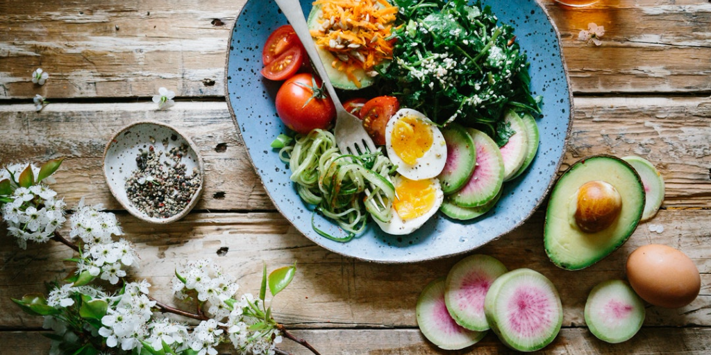 A plate of food with vegetables and eggs on a wooden table.