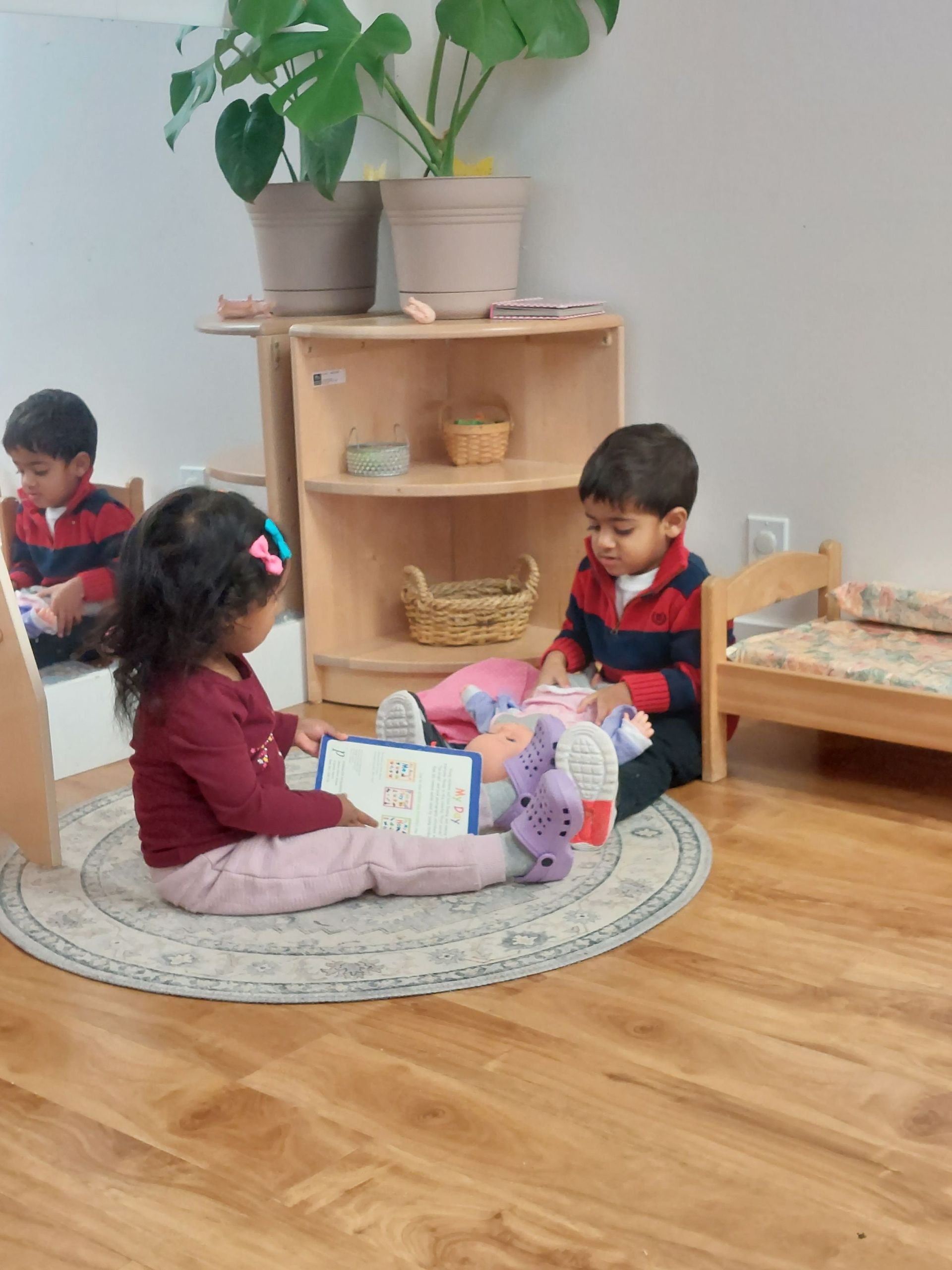 A boy and a girl are sitting on the floor playing with toys.