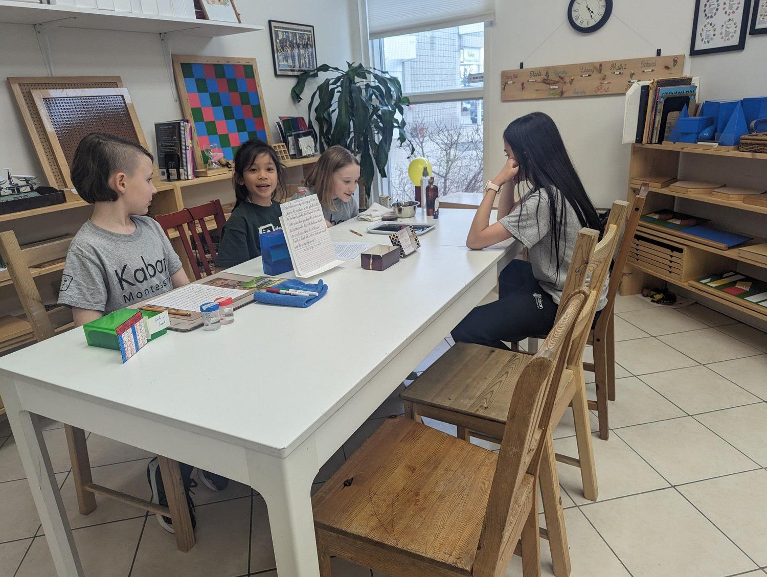 A group of children are sitting at a table in a classroom.