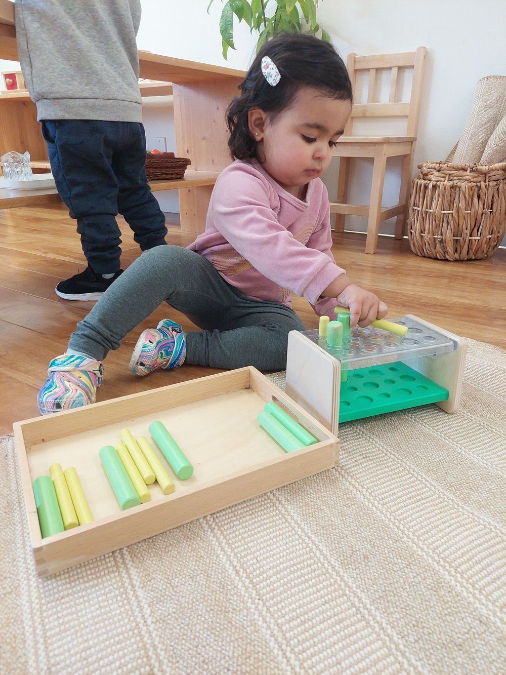 A little girl is sitting on the floor playing with a toy.