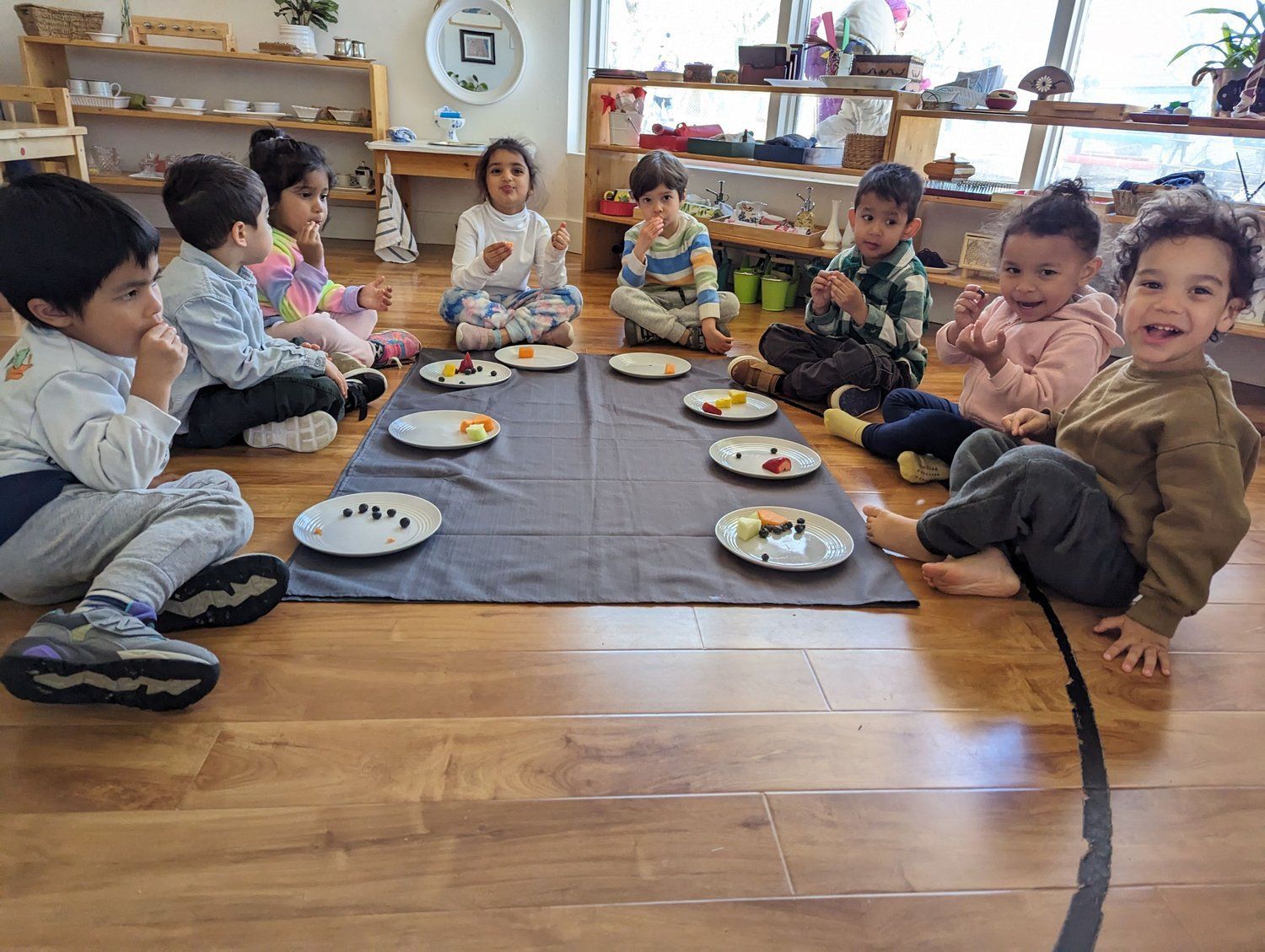 A group of children are sitting on the floor eating food.