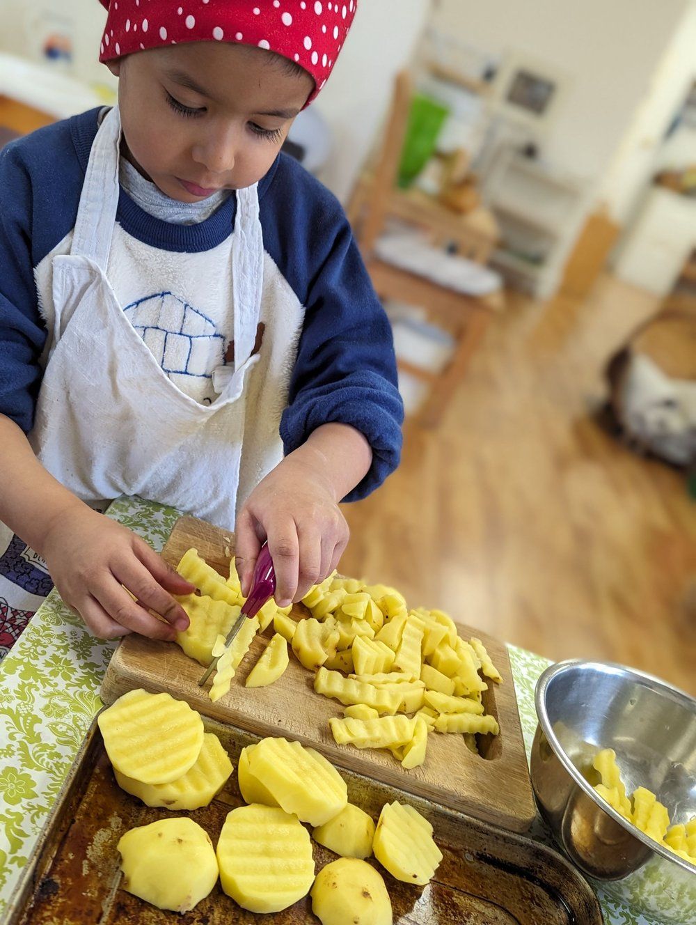 A young boy is cutting potatoes on a cutting board.