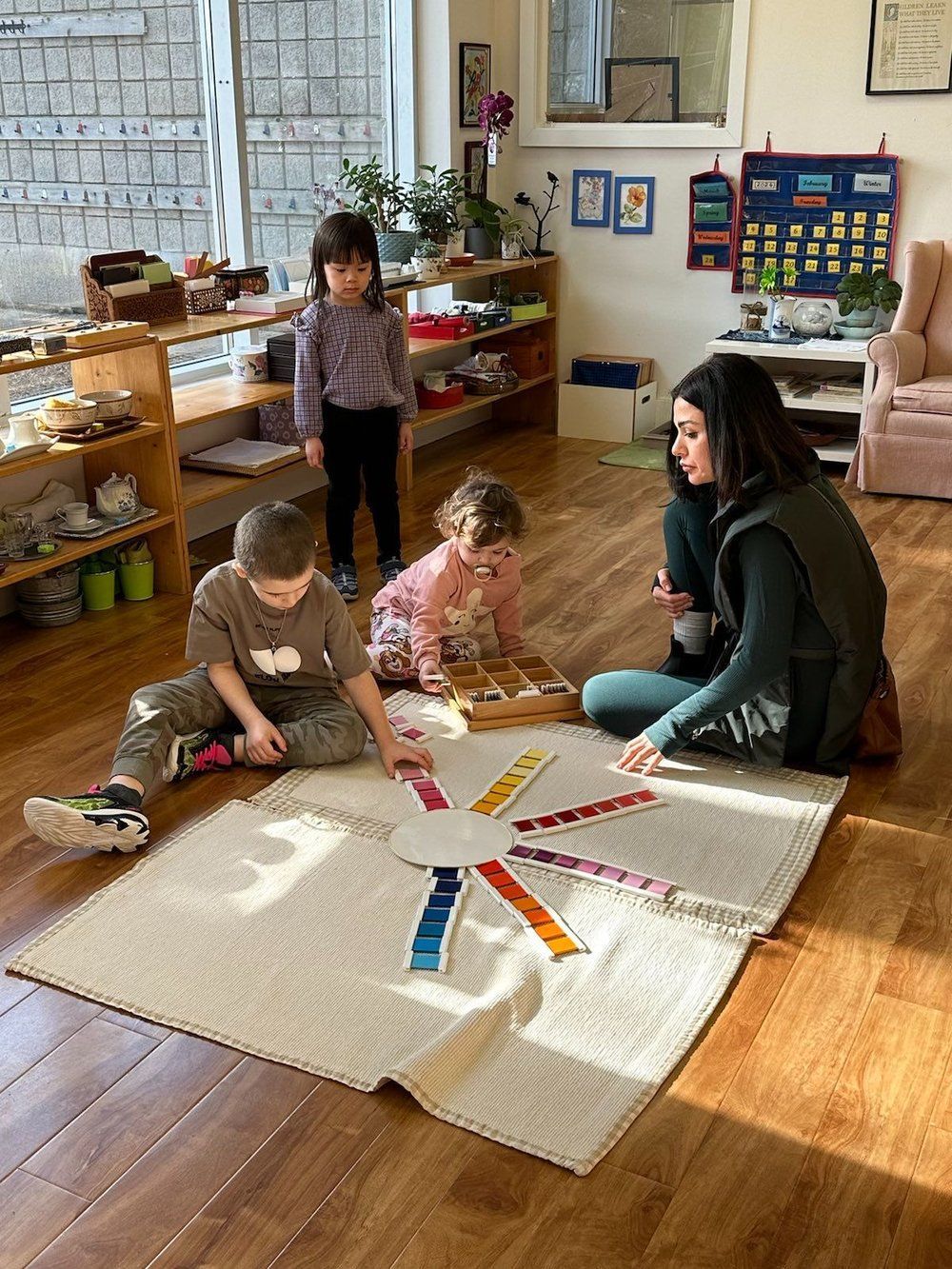 A group of children are sitting on the floor playing with a teacher.