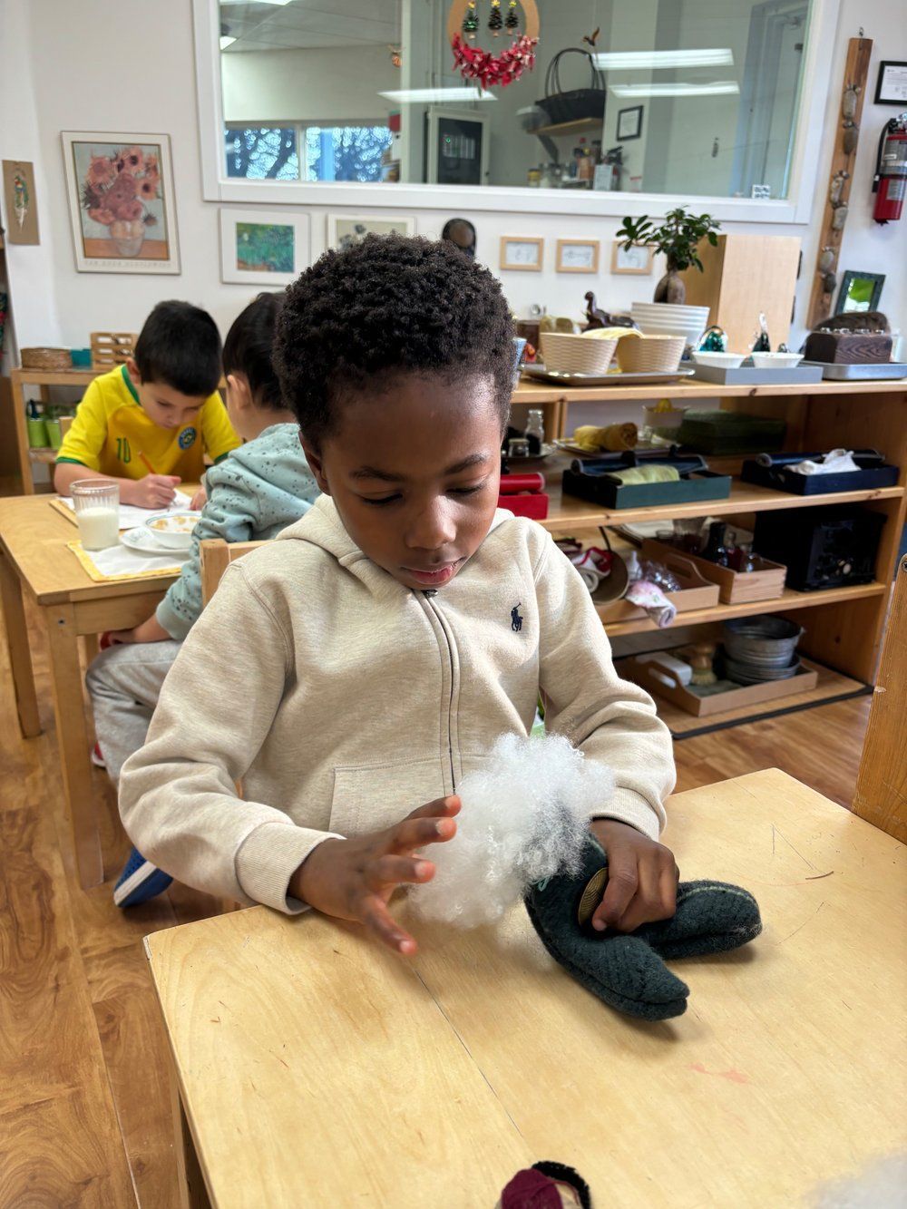 A young boy is sitting at a table playing with a stuffed animal.