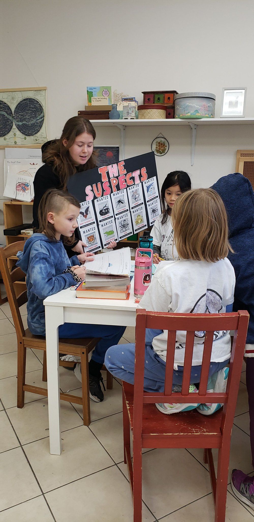 A group of children are sitting at a table in a classroom.