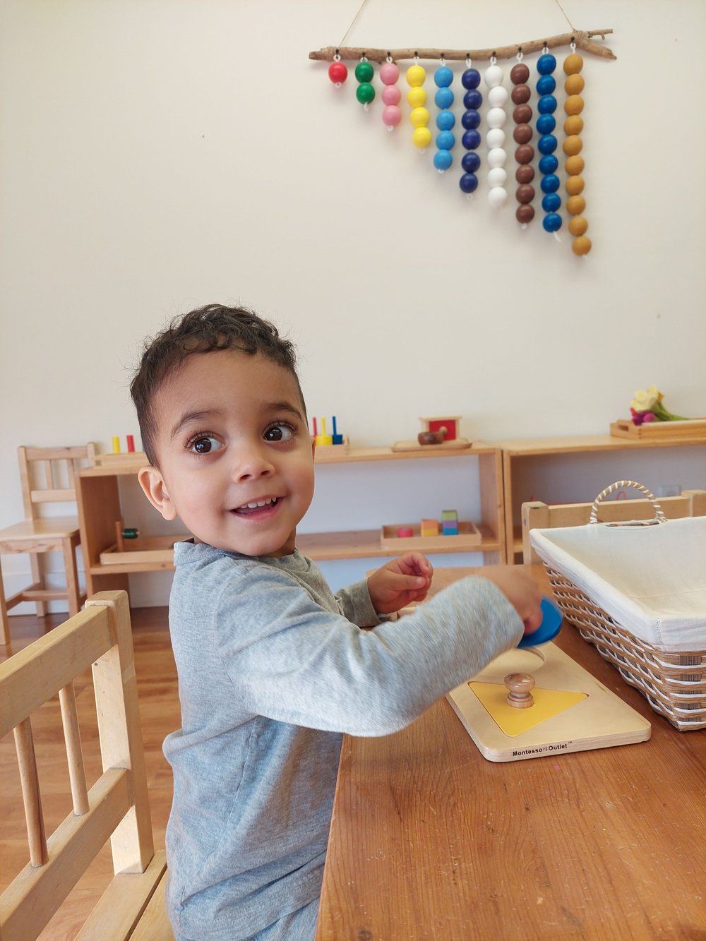 A young boy is sitting at a wooden table playing with toys.