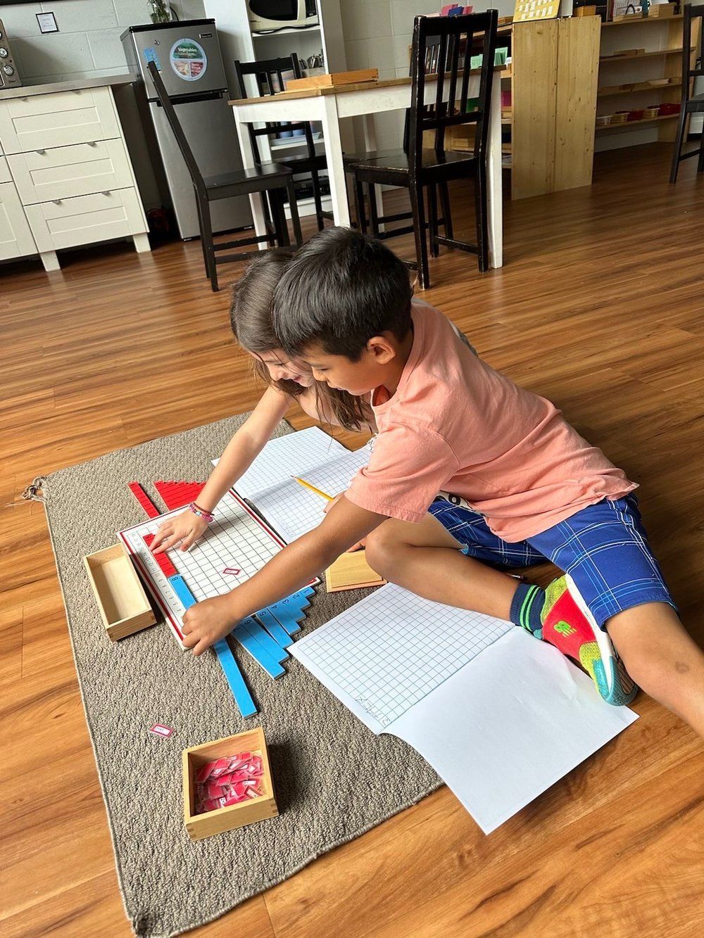 A young boy is sitting on the floor doing his homework.