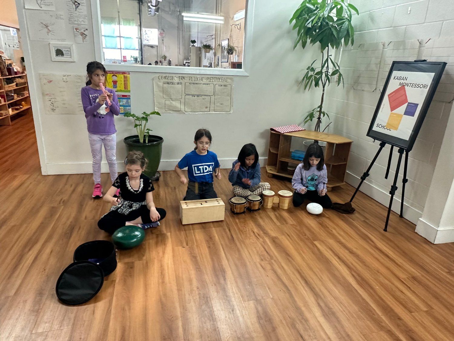 A group of children are sitting on the floor playing musical instruments.
