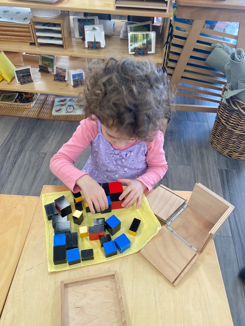 A little girl is sitting at a table playing with wooden blocks.
