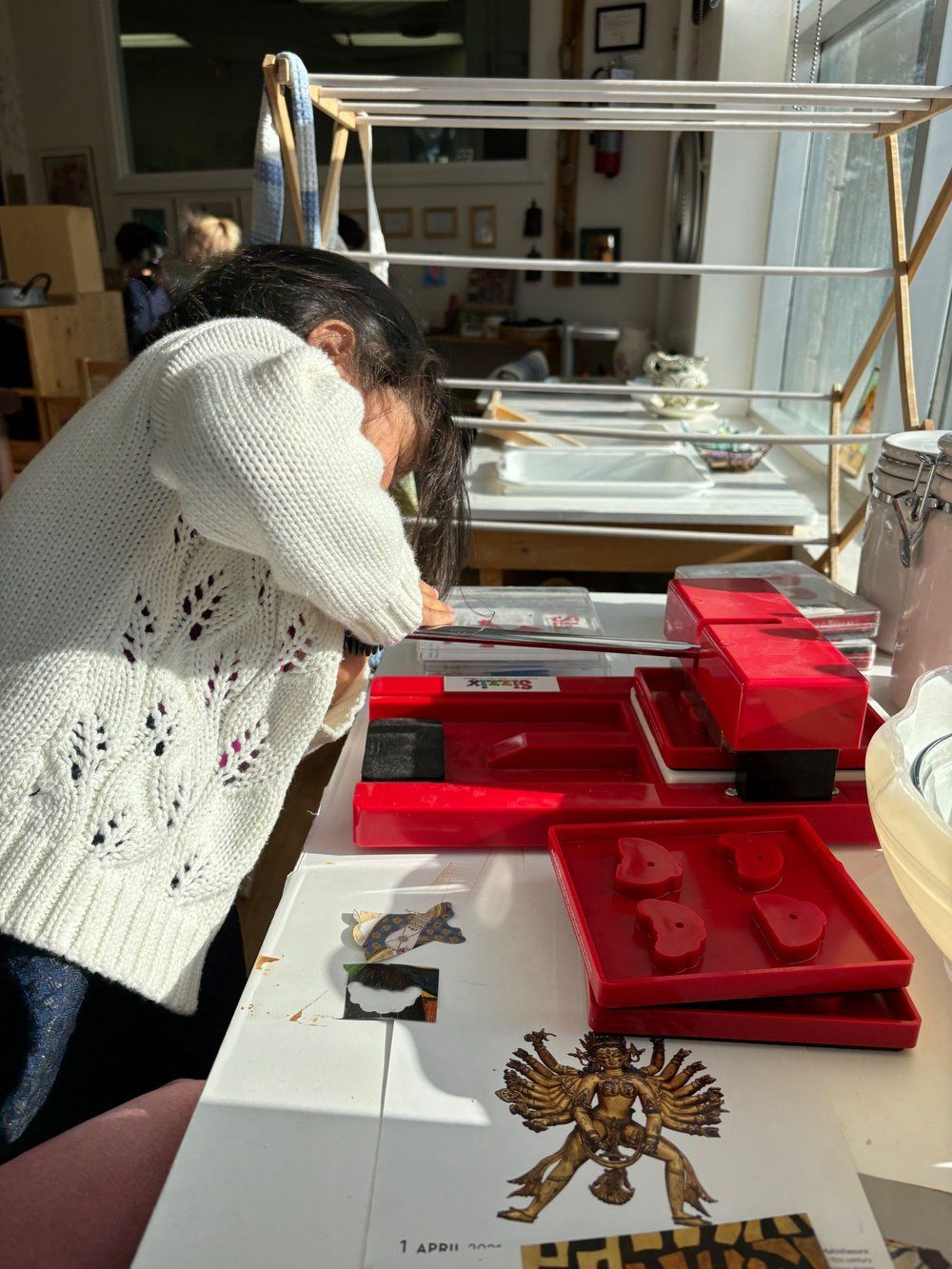 A woman is sitting at a table using a machine.