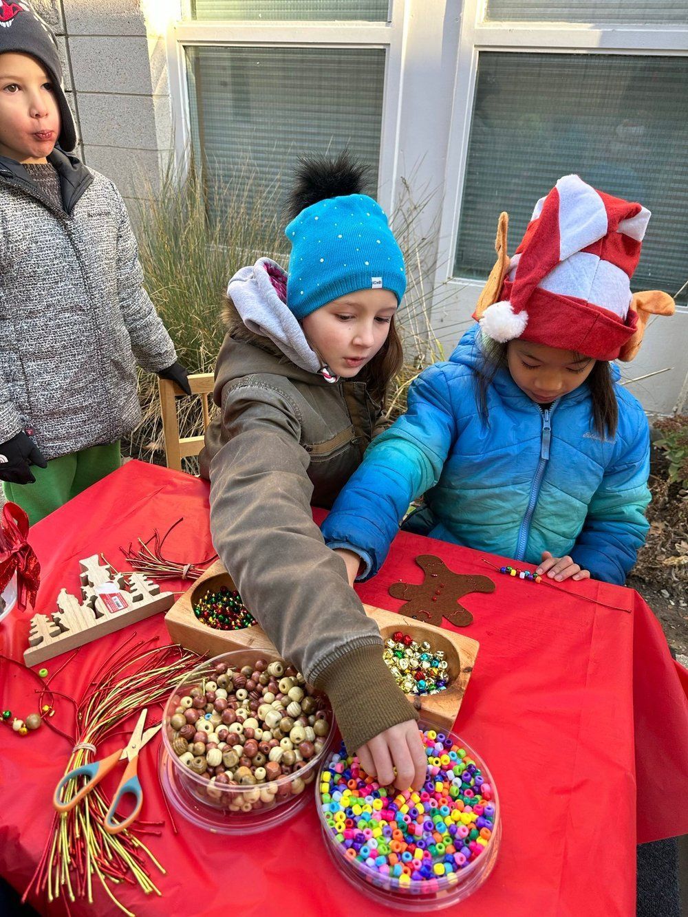 A group of children are sitting at a table playing with beads.