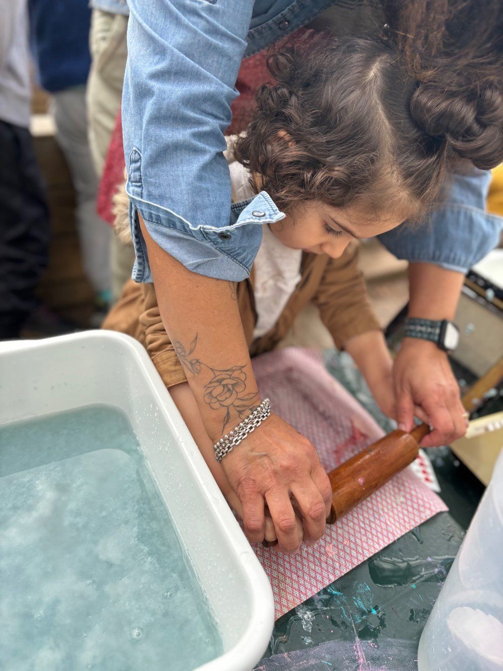A woman is teaching a little girl how to use a rolling pin.
