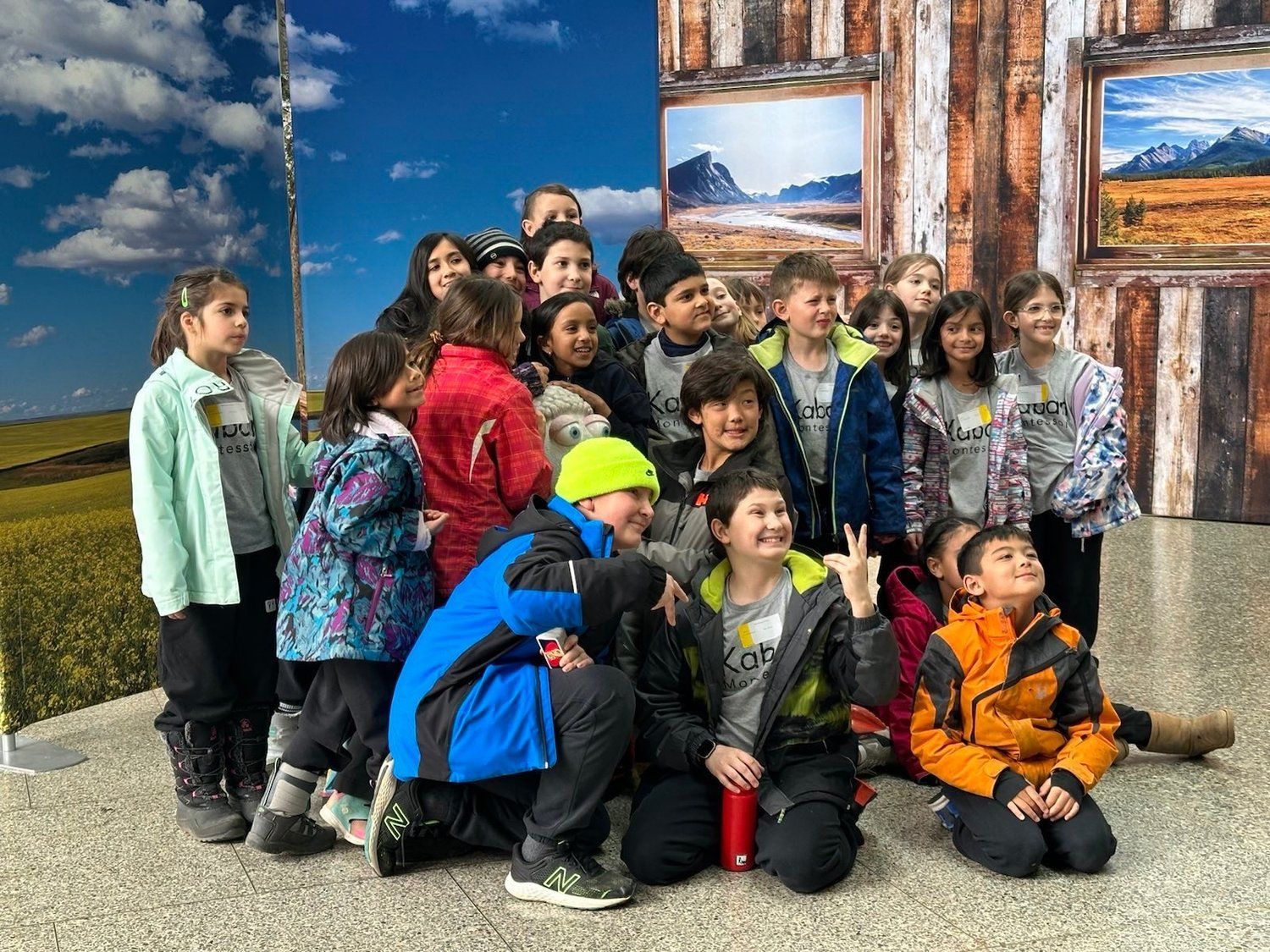 A group of children are posing for a picture in front of a wooden wall.