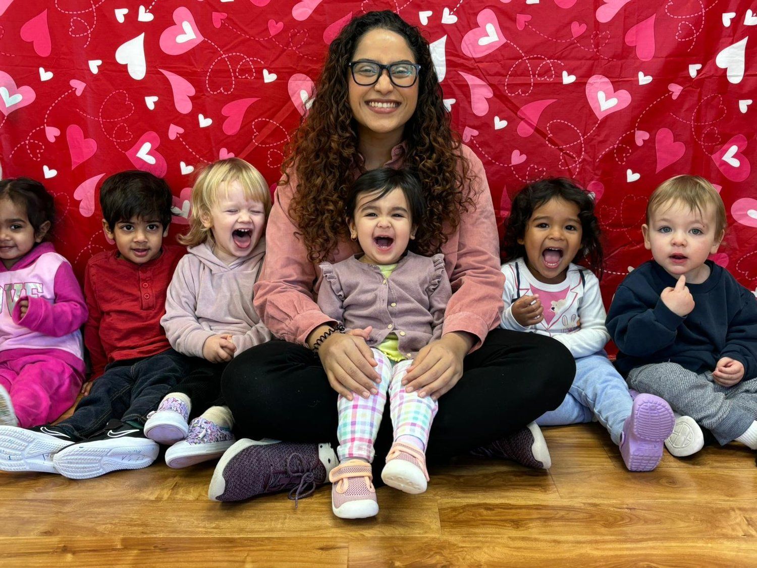 A woman is sitting on the floor with a group of children.