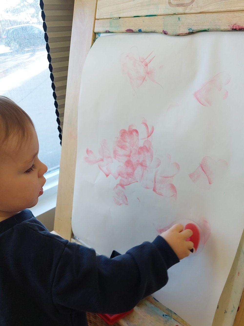 A little boy is painting on a piece of paper