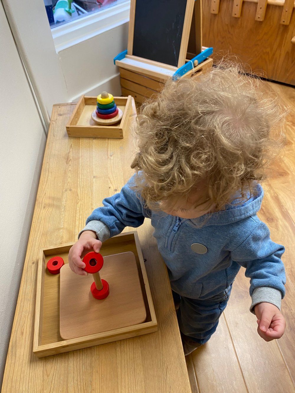 A little boy is playing with a wooden toy on a wooden table.