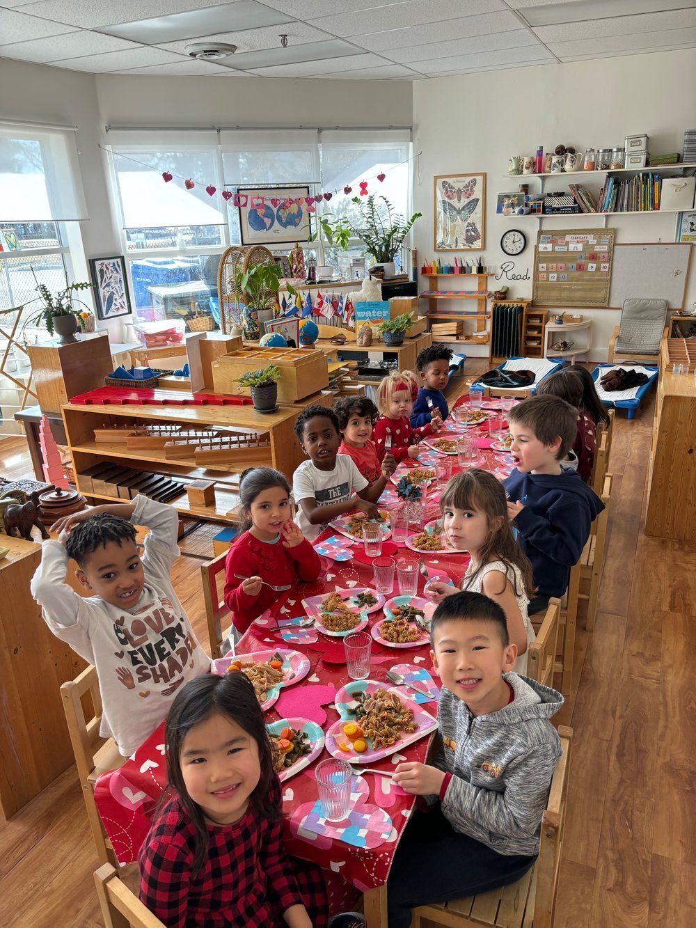 A group of children are sitting at a long table eating food.