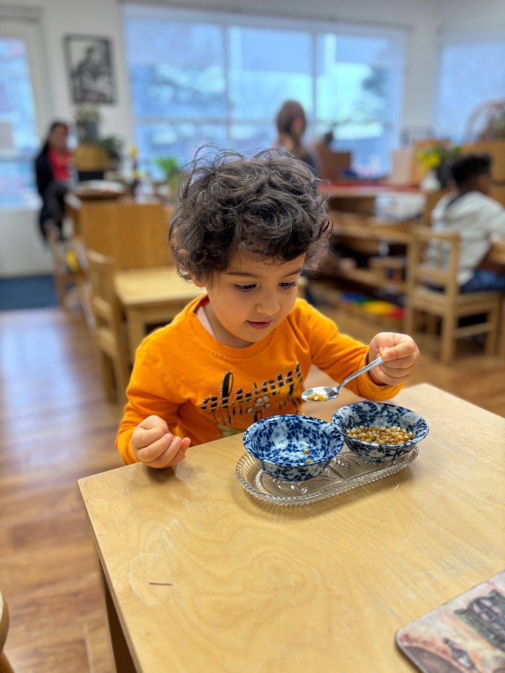 A young boy is sitting at a table eating cereal with a spoon.