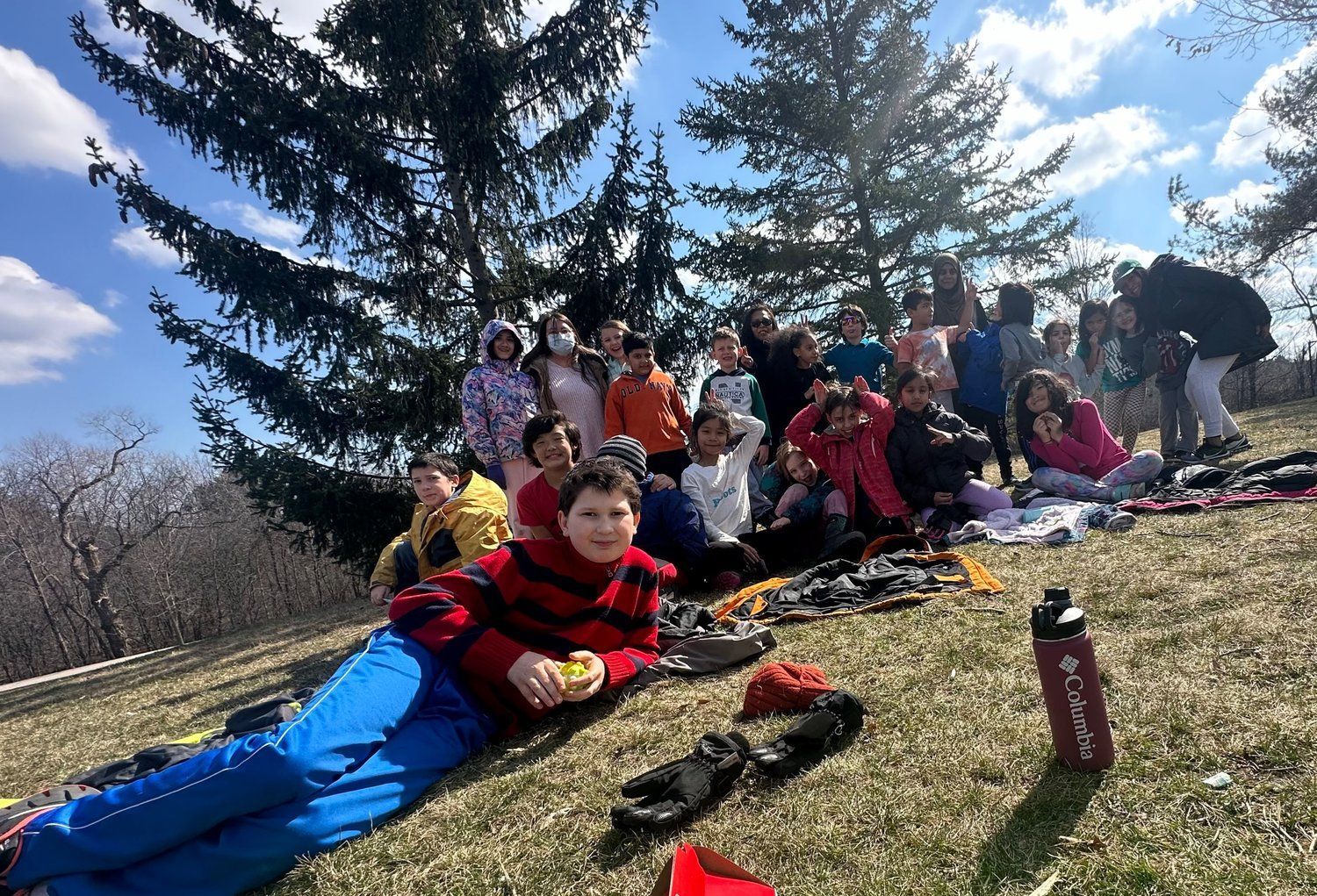A group of people are laying in the grass under a tree.