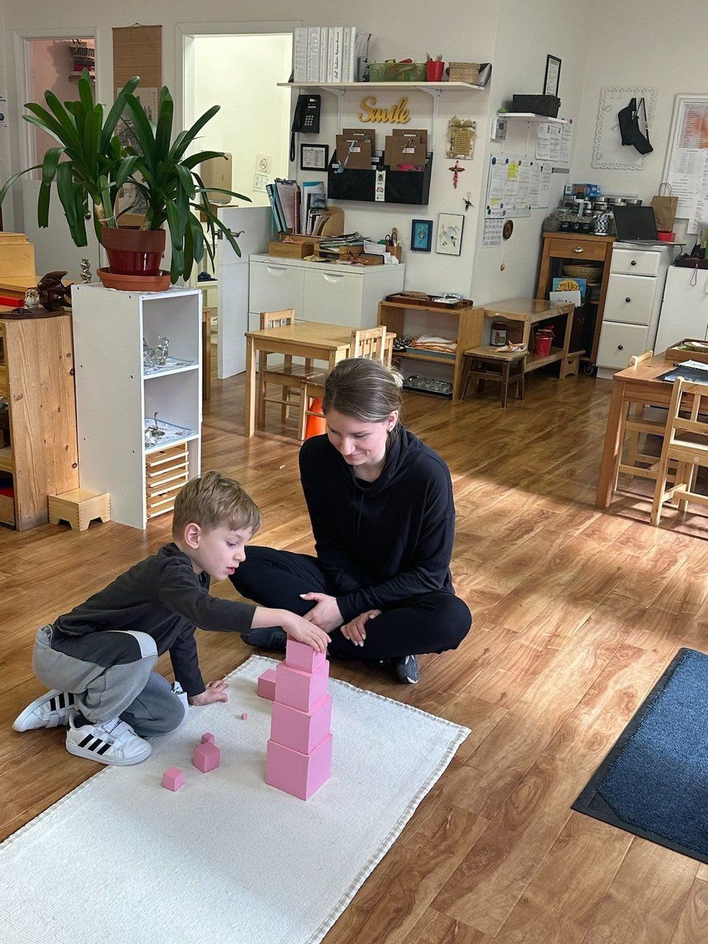 A woman and a child are playing with pink blocks in a room.
