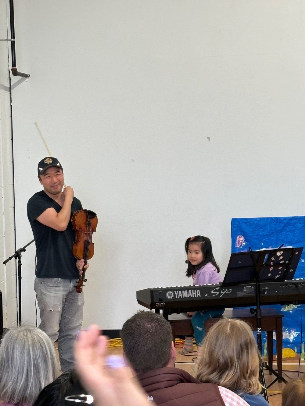 A man playing a violin in front of a yamaha keyboard