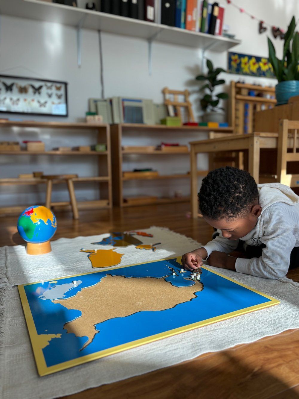 A young boy is laying on the floor playing with a map of the world.