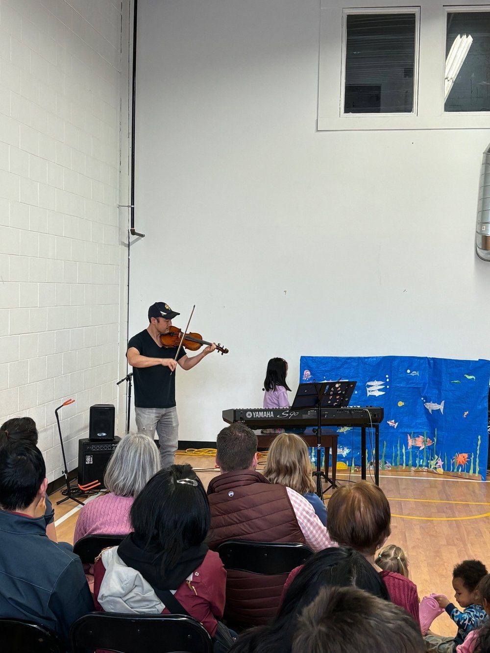A man is playing a violin in front of a group of people.