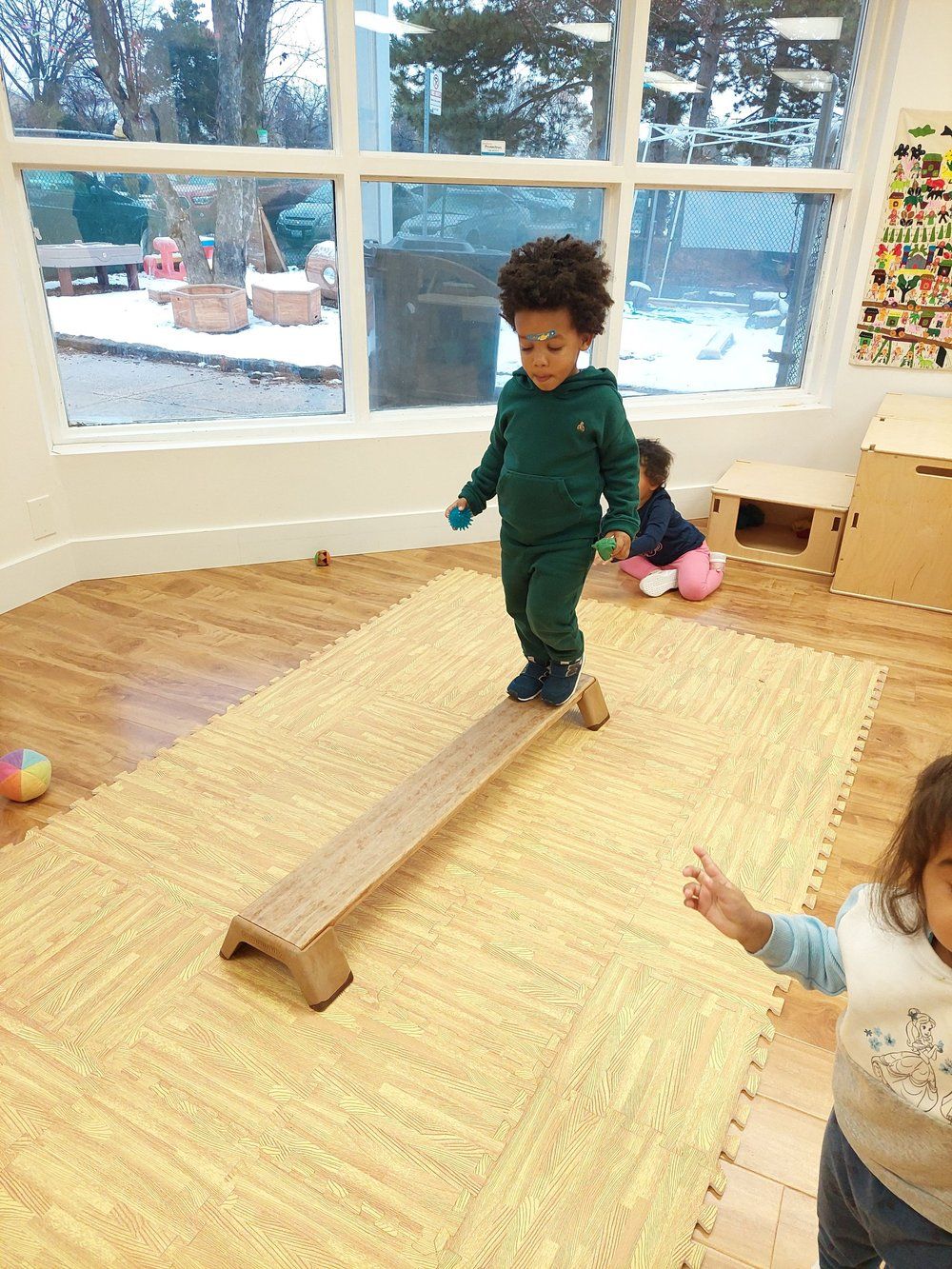 A young boy is standing on a balance beam in a room.